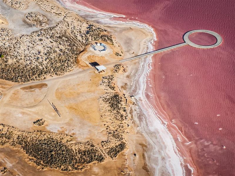 Aerial image of pink Lake Tyrrell showing viewing platform and sand coloured lake edge.