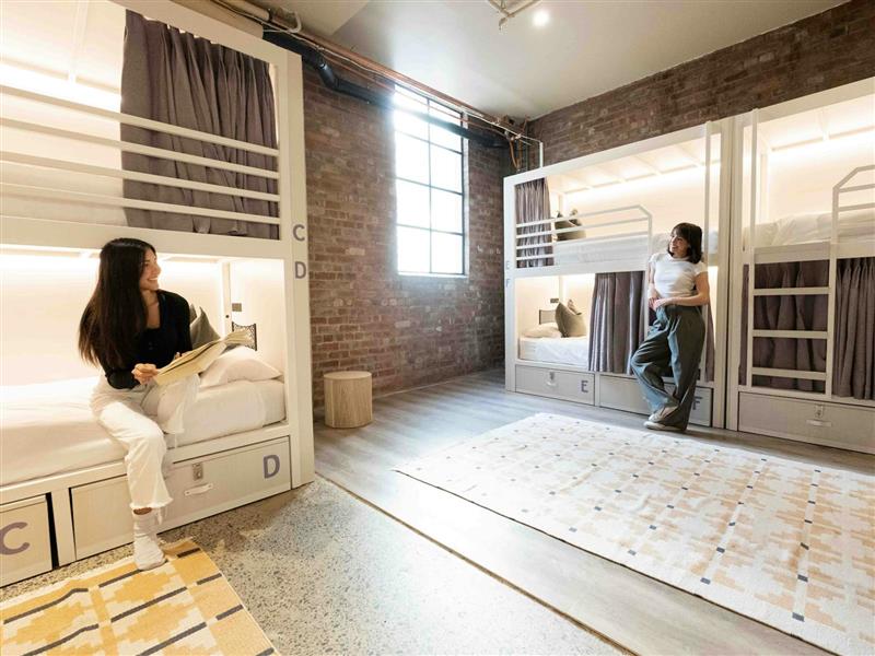 Two guests in a hostel dorm chatting