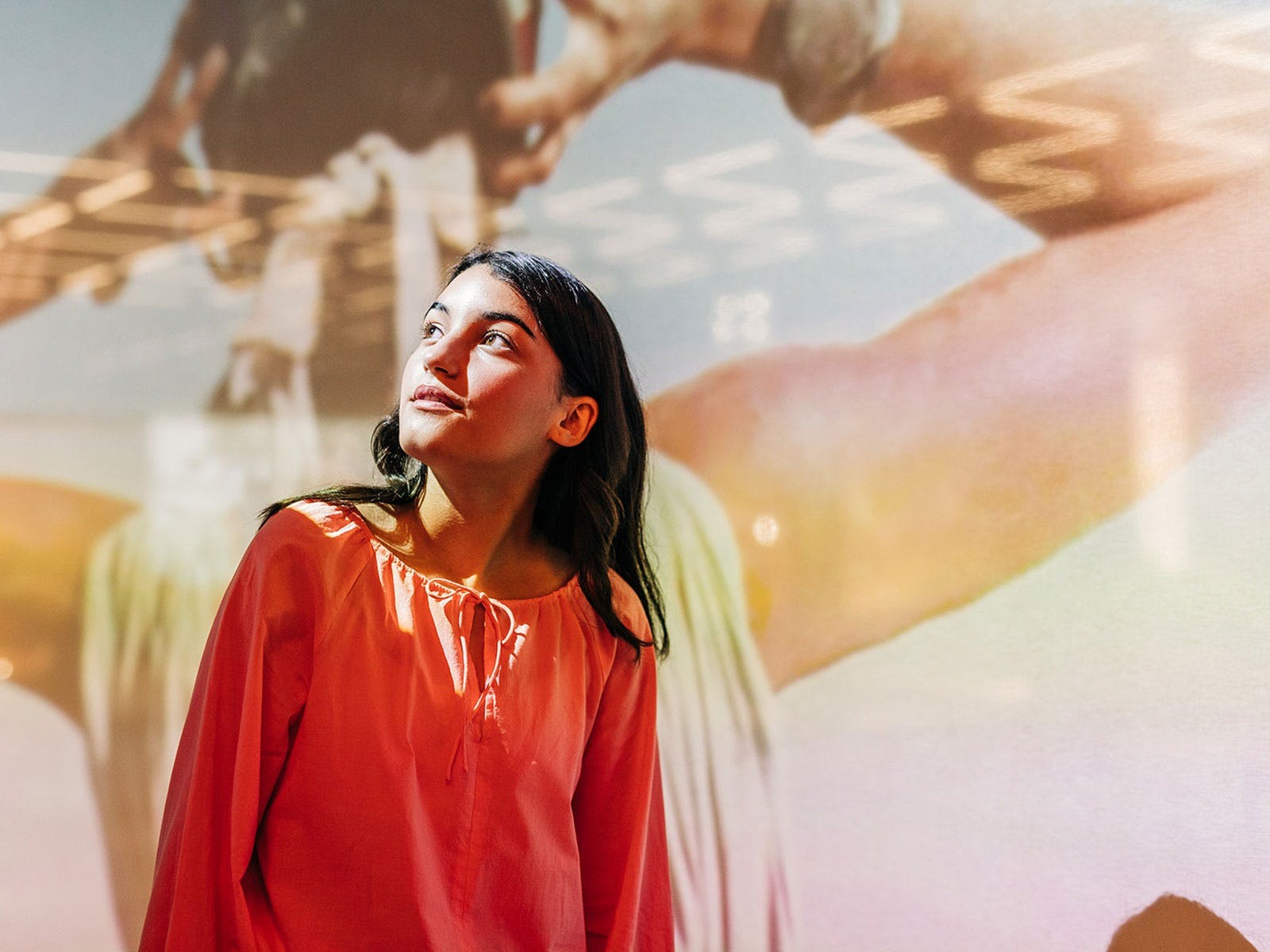 A girl looks over her shoulder, with a projected artwork behind her