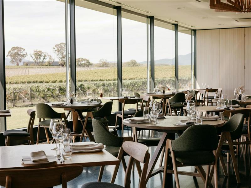 The interior of Oakridge Restaurant, with elegant wooden chairs and a view of the vineyard