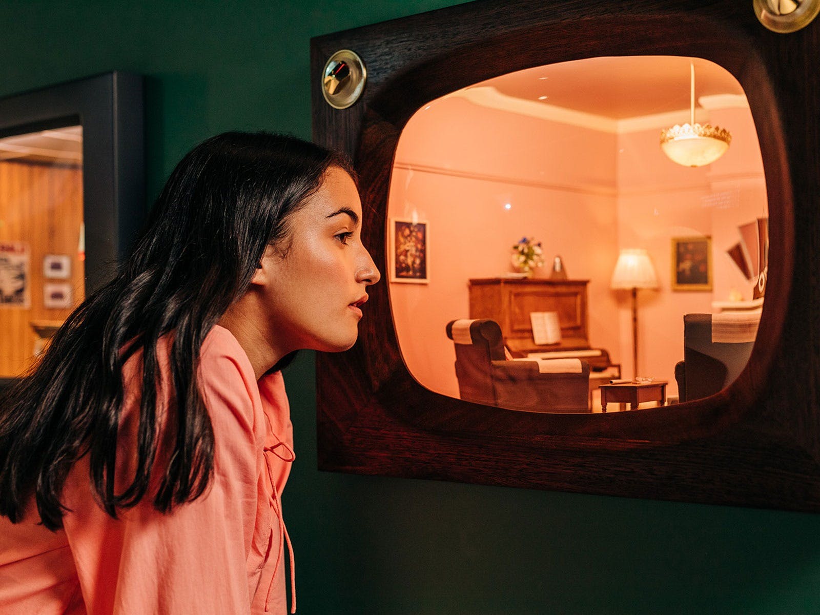 a girl looks into a miniature diorama of a loungeroom setting